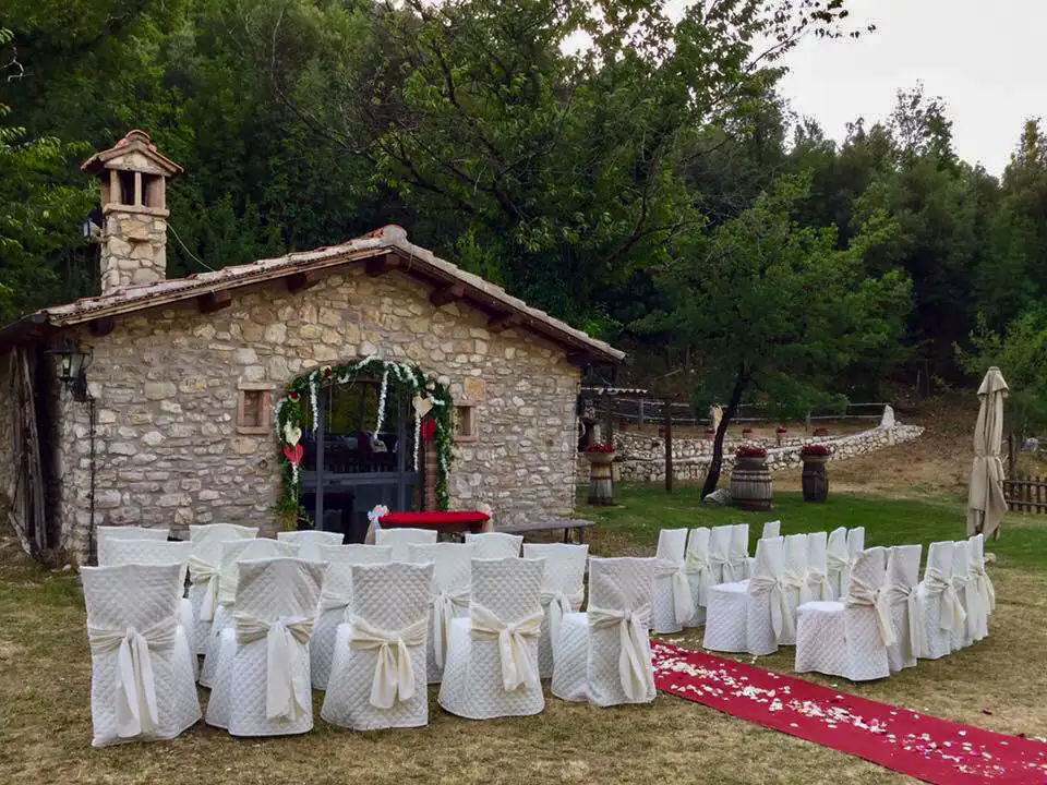 Casetta delle Delizie allestita per matrimonio con sedie nel giardino e altare di fronte alla casetta.
